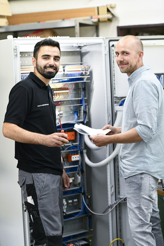 Ammar Tbateb Tasoun (l.) aus Syrien ist einer von drei Auszubildenden bei Elektro Binkowski in Recklinghausen. Er erlernt dort das Elektronikerhandwerk (Automatisierungstechnik). Als der Geflüchtete seine Lehre im August 2018 begann, konnte er kaum Deutsch. Trotz der Sprachbarriere stellte Juniorchef Thomas Binkowski (r.) den 24-Jährigen gern ein – zunächst für eine Einstiegsqualifizierung, bei der Tbateb Tasoun ein Langzeitpraktikum absolvierte; anschließend übernahm er ihn nach Rücksprache mit der Schule wegen guter Leistungen direkt ins zweite Lehrjahr. Tbateb Tasoun, der bereits in seiner Heimat und Libyen als Elektriker gearbeitet hat, ohne den Beruf je formell erlernt zu haben, überzeugte durch Fleiß und Hilfsbereitschaft. Sprachbarrieren ließen sich mit Geduld des ganzen Teams überwinden.